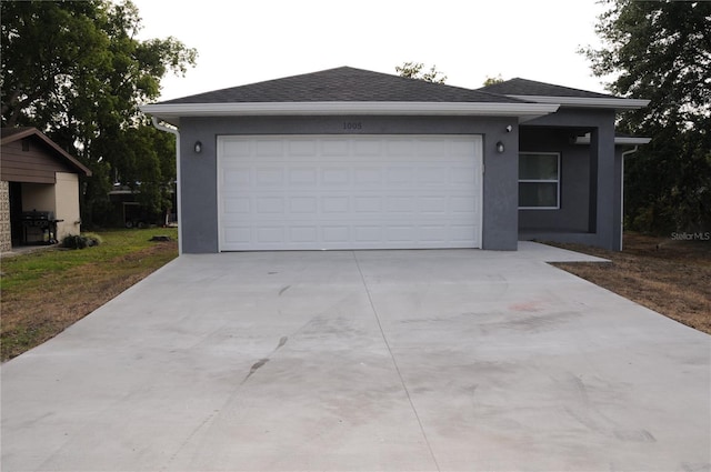 single story home featuring stucco siding, an attached garage, roof with shingles, and concrete driveway