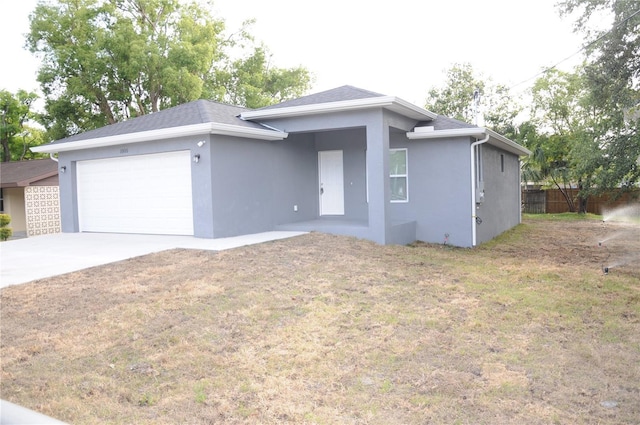 view of front facade featuring a front lawn, driveway, an attached garage, fence, and stucco siding