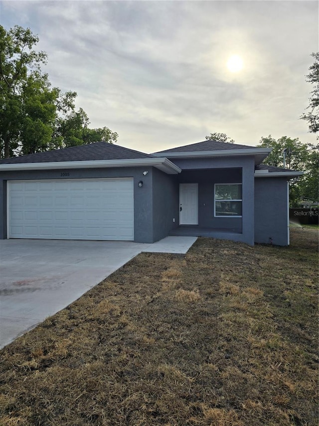 view of front of property with concrete driveway, an attached garage, a front yard, and stucco siding