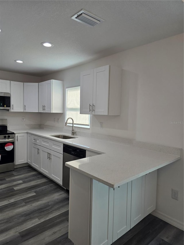 kitchen featuring a sink, stainless steel appliances, a peninsula, white cabinetry, and visible vents