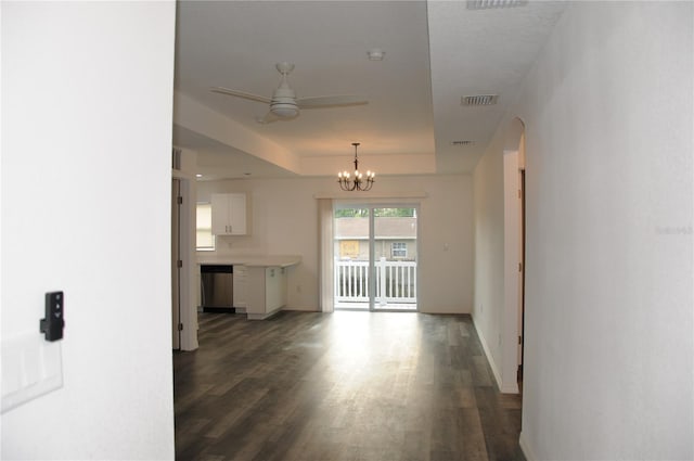 unfurnished living room featuring a tray ceiling, baseboards, visible vents, ceiling fan with notable chandelier, and wood finished floors