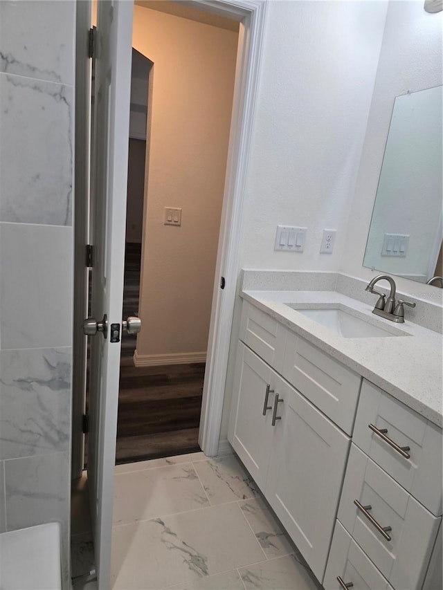 bathroom featuring baseboards, marble finish floor, and vanity