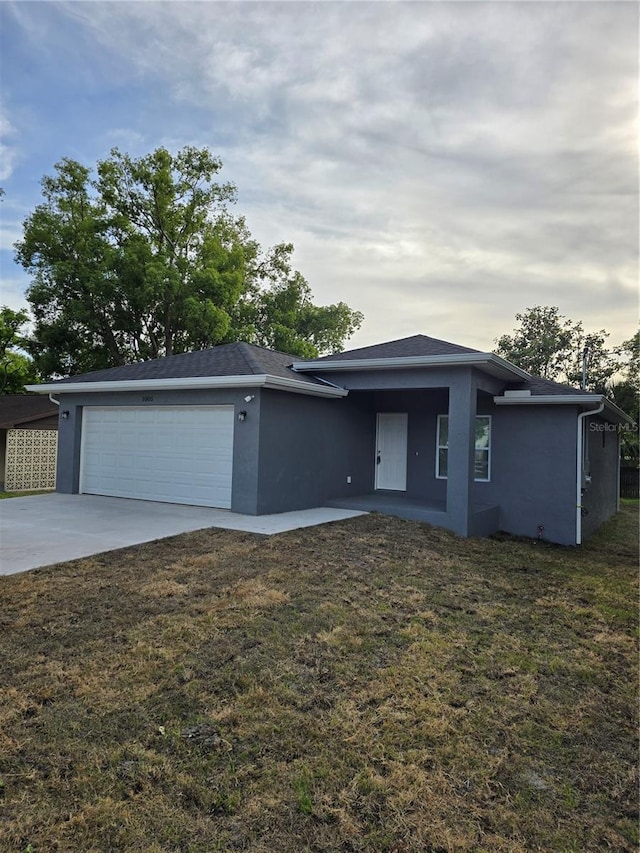 view of front facade featuring a garage, driveway, a front yard, and stucco siding