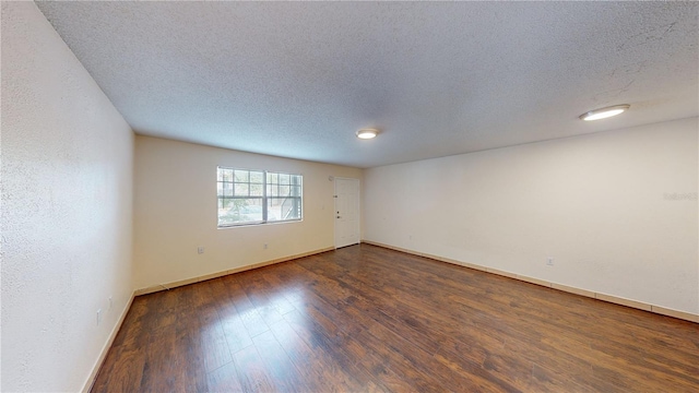 empty room with dark hardwood / wood-style floors and a textured ceiling