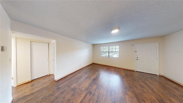 spare room featuring dark wood-type flooring and a textured ceiling