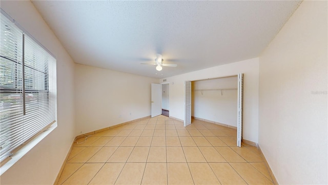 unfurnished bedroom featuring a textured ceiling, a closet, ceiling fan, and light tile patterned flooring