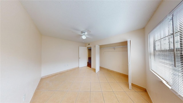 unfurnished bedroom with ceiling fan, a textured ceiling, a closet, and light tile patterned floors