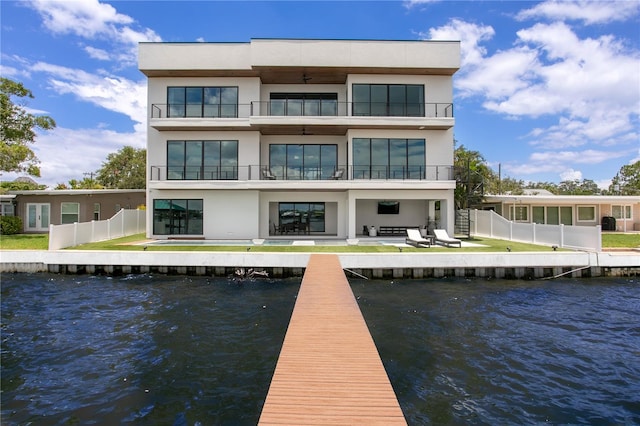 back of property featuring a lawn, a water view, a balcony, and a patio