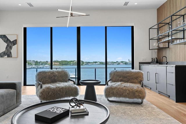 living room with sink, a water view, and light hardwood / wood-style floors