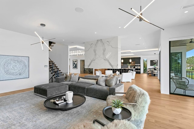 living room with light hardwood / wood-style floors and ceiling fan with notable chandelier