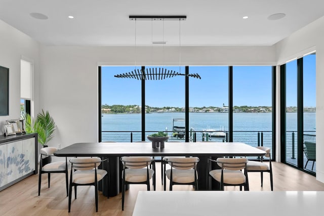 dining area with light hardwood / wood-style flooring and a water view