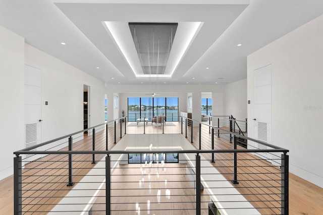 hallway featuring a raised ceiling and light hardwood / wood-style floors