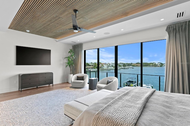 bedroom featuring hardwood / wood-style floors, ceiling fan, a water view, and access to outside