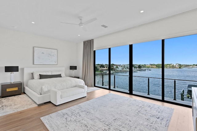 bedroom with access to exterior, ceiling fan, a water view, and light hardwood / wood-style floors