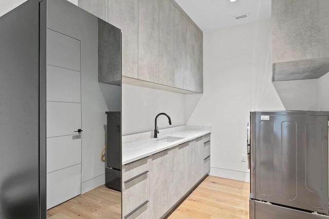 laundry room with light hardwood / wood-style floors, cabinets, and sink