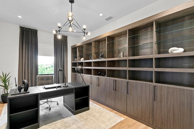 home office with light wood-type flooring and an inviting chandelier