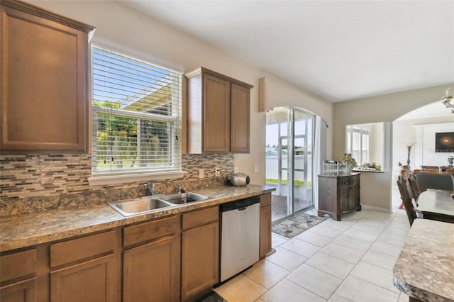 kitchen with stainless steel dishwasher, light tile patterned floors, sink, and tasteful backsplash