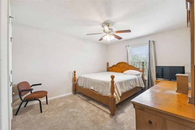 bedroom with a textured ceiling, light colored carpet, and ceiling fan