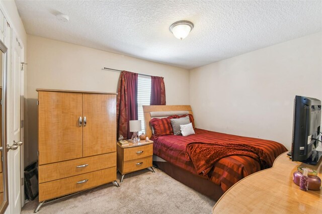 bedroom with a textured ceiling and light carpet