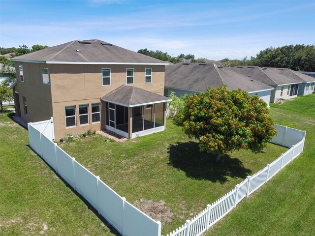 back of property featuring a lawn and a sunroom