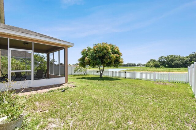 view of yard with a sunroom and a water view