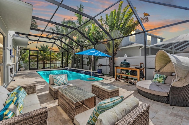 pool at dusk with outdoor lounge area, pool water feature, a patio area, and a lanai