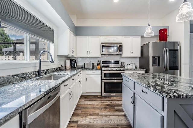 kitchen with backsplash, dark wood-type flooring, stainless steel appliances, pendant lighting, and sink