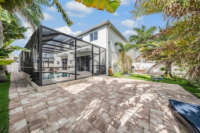 rear view of house with a patio, glass enclosure, and a fenced in pool