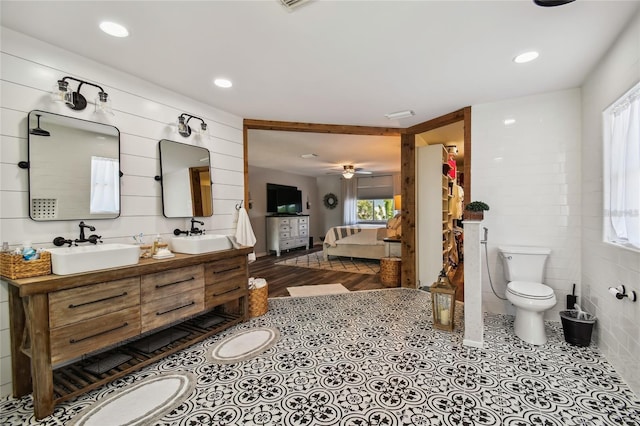 bathroom featuring tile walls, toilet, a wealth of natural light, and ceiling fan