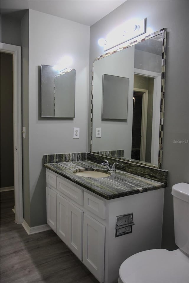 bathroom with wood-type flooring, vanity, and toilet