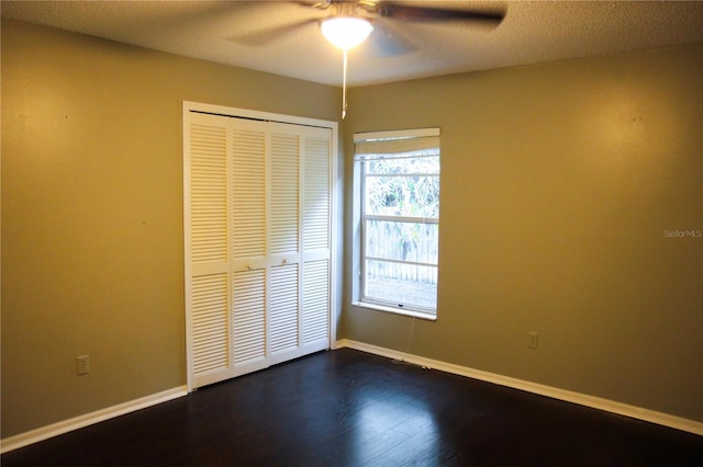 unfurnished bedroom with a closet, dark hardwood / wood-style floors, ceiling fan, and a textured ceiling