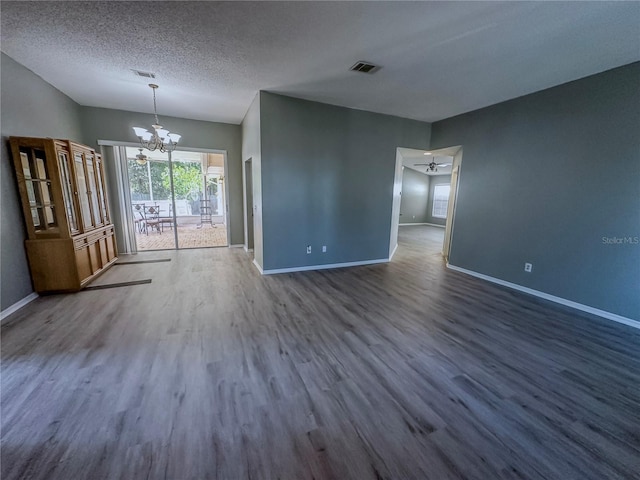 interior space with a notable chandelier, a textured ceiling, and dark wood-type flooring