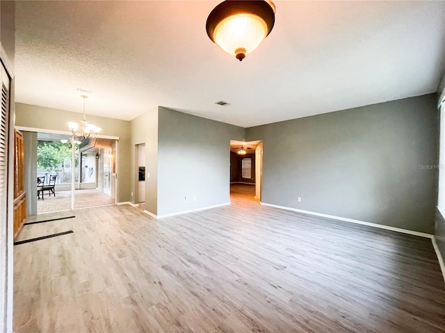 unfurnished living room with a notable chandelier, hardwood / wood-style floors, and a textured ceiling