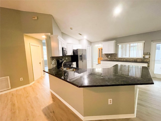 kitchen with white cabinets, sink, appliances with stainless steel finishes, vaulted ceiling, and decorative backsplash