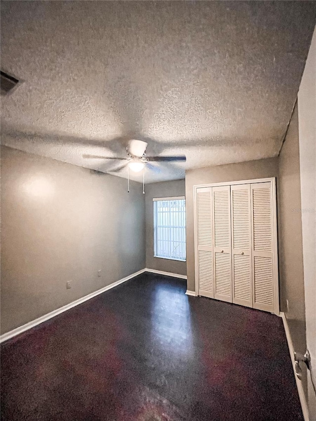 unfurnished bedroom with ceiling fan, a textured ceiling, and a closet