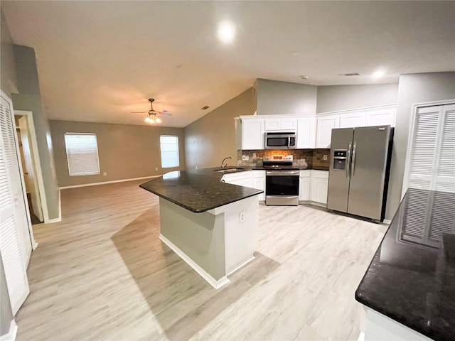 kitchen with ceiling fan, lofted ceiling, kitchen peninsula, white cabinetry, and appliances with stainless steel finishes