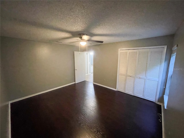 unfurnished bedroom with a textured ceiling, dark hardwood / wood-style flooring, ceiling fan, and a closet