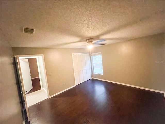 unfurnished bedroom with a textured ceiling, dark hardwood / wood-style floors, ceiling fan, and a closet