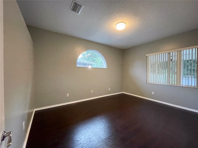 spare room featuring a textured ceiling and hardwood / wood-style floors