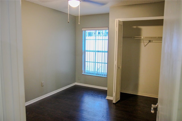 unfurnished bedroom with dark hardwood / wood-style flooring, ceiling fan, and a closet