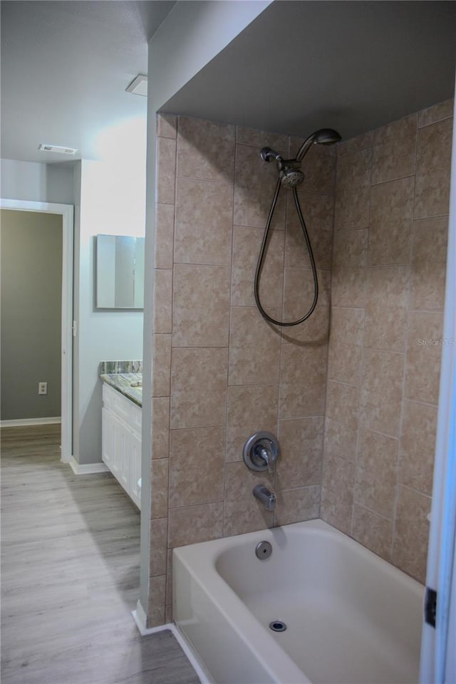 bathroom featuring wood-type flooring, vanity, and tiled shower / bath