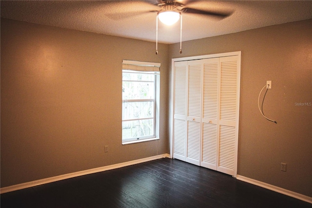 unfurnished bedroom with ceiling fan, a textured ceiling, a closet, and dark hardwood / wood-style floors