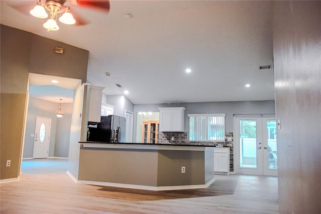 kitchen featuring decorative backsplash, white cabinets, stainless steel refrigerator, light wood-type flooring, and lofted ceiling