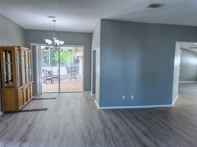 unfurnished dining area featuring a textured ceiling, ceiling fan with notable chandelier, and hardwood / wood-style flooring