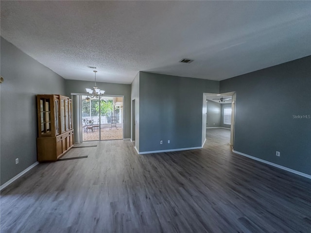 empty room featuring a textured ceiling, ceiling fan with notable chandelier, and dark hardwood / wood-style flooring