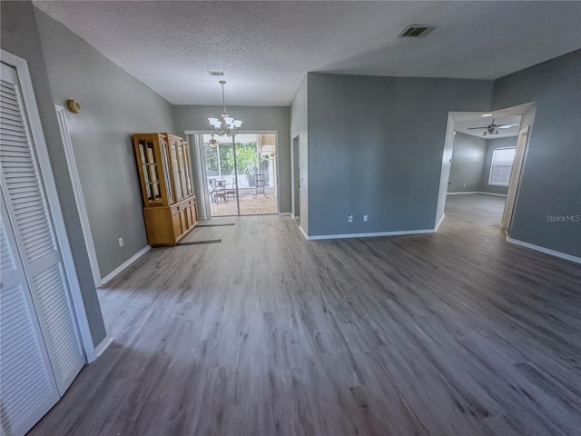 unfurnished dining area with wood-type flooring, a textured ceiling, and ceiling fan with notable chandelier