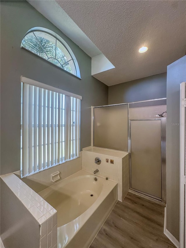 bathroom featuring a textured ceiling, shower with separate bathtub, and wood-type flooring