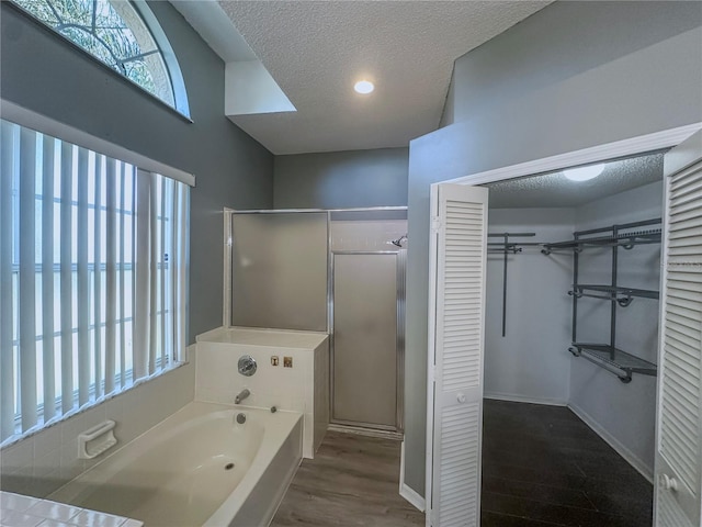 bathroom featuring a textured ceiling, hardwood / wood-style flooring, and separate shower and tub