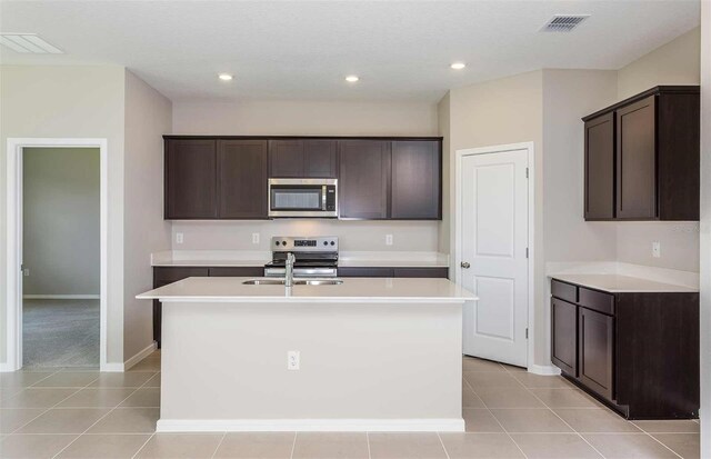 8322 SW 52nd Lane Rd, Ocala, FL 34481 - kitchen with dark brown cabinetry, appliances with stainless steel finishes, baseboards, light tile patterned floors, and a center island with sink