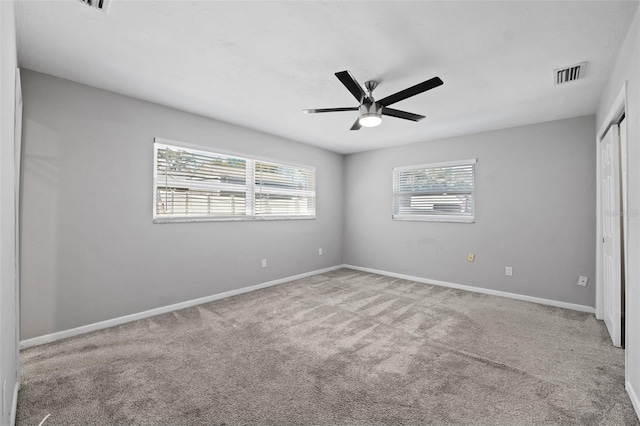 unfurnished bedroom featuring multiple windows, ceiling fan, and light carpet